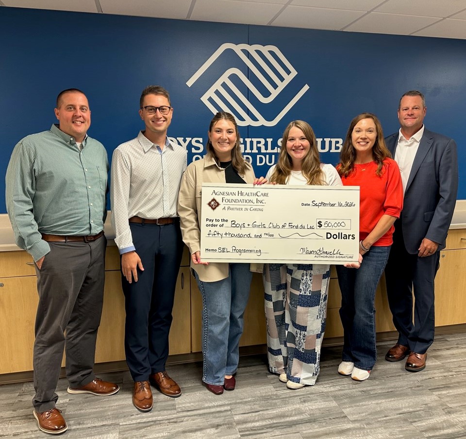 A group of six people with a big check