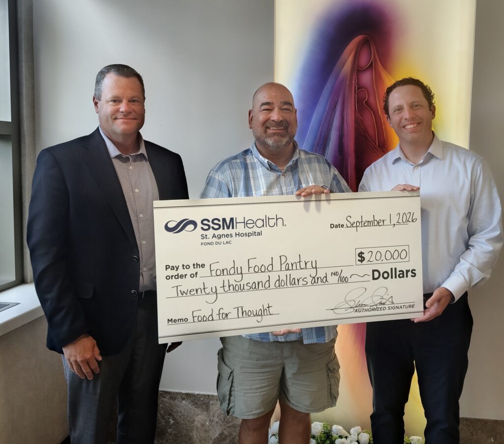 Three men inside holding a large check