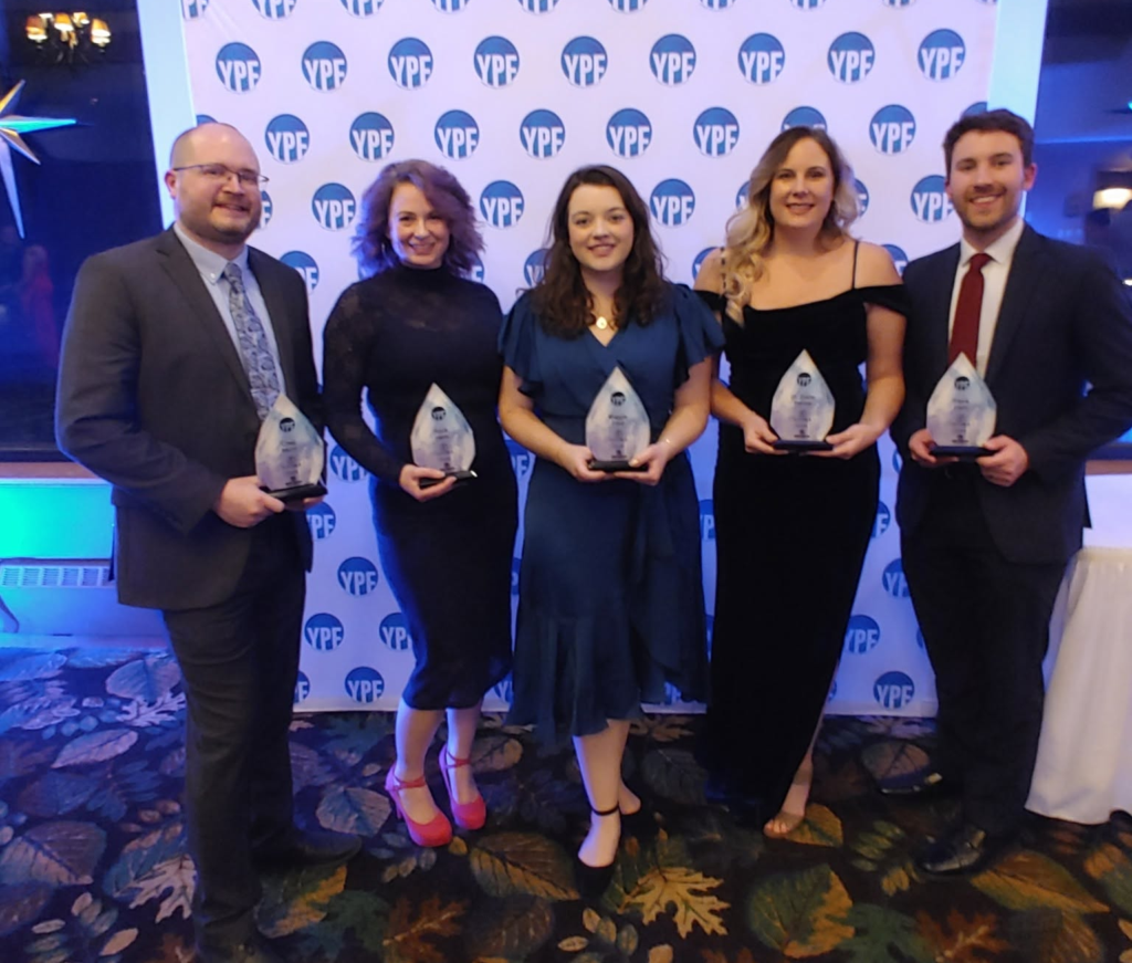 Five people standing with glass awards