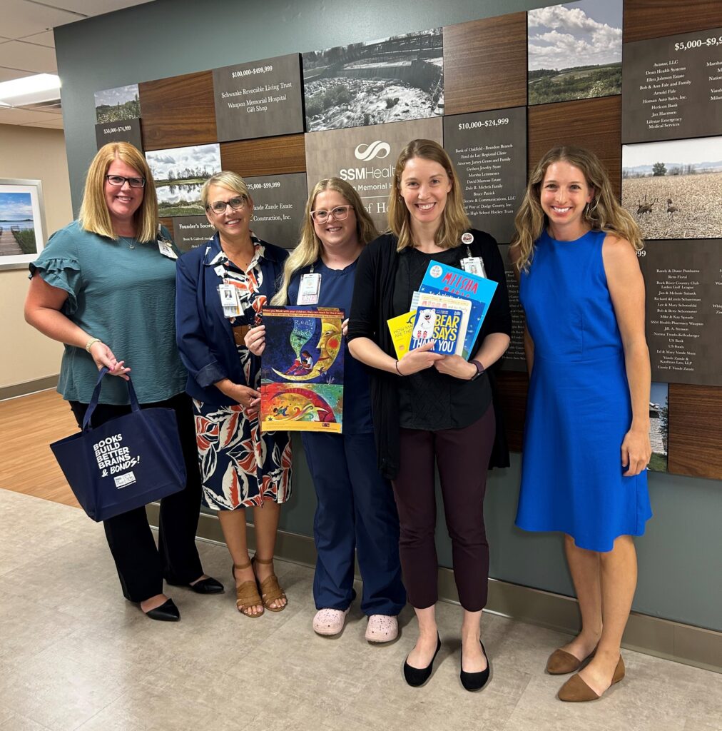 Five women in a hallway holding books