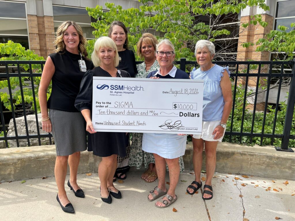 Six women outside holding a big check