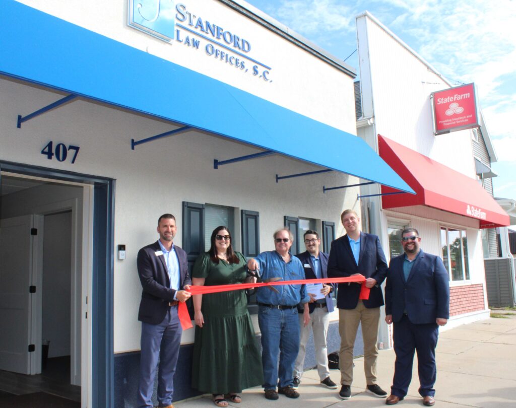 A small group of people outside for a ribbon cutting