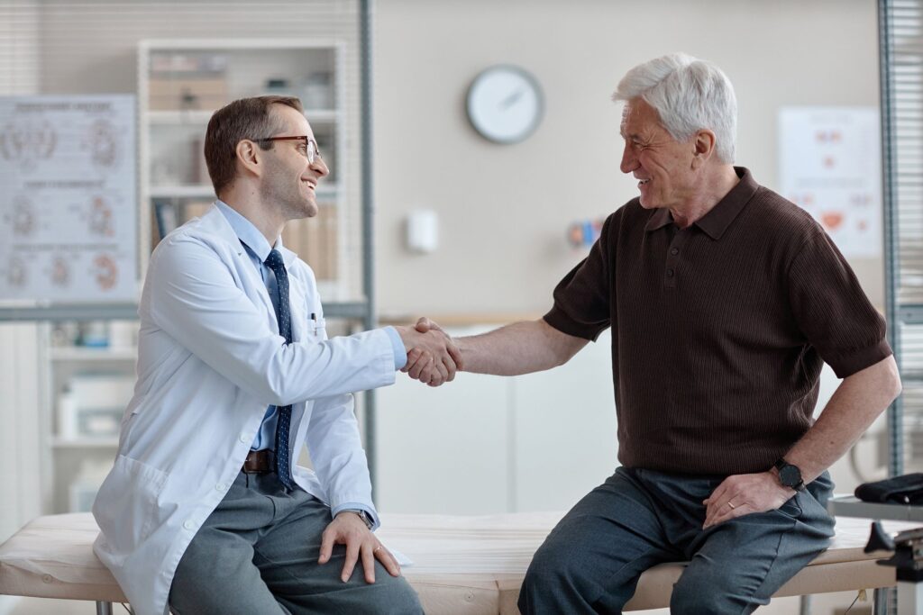 A doctor and an older male patient shaking hands