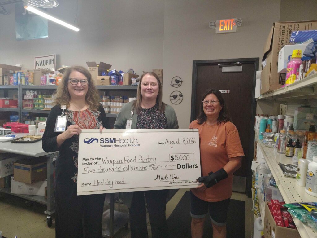 Three women inside a store with a big check