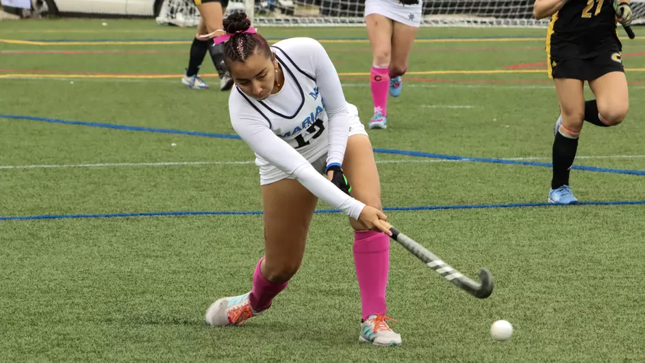Women playing college field hockey