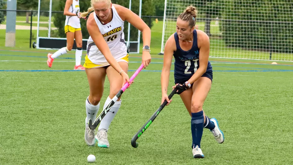 Women playing college field hockey