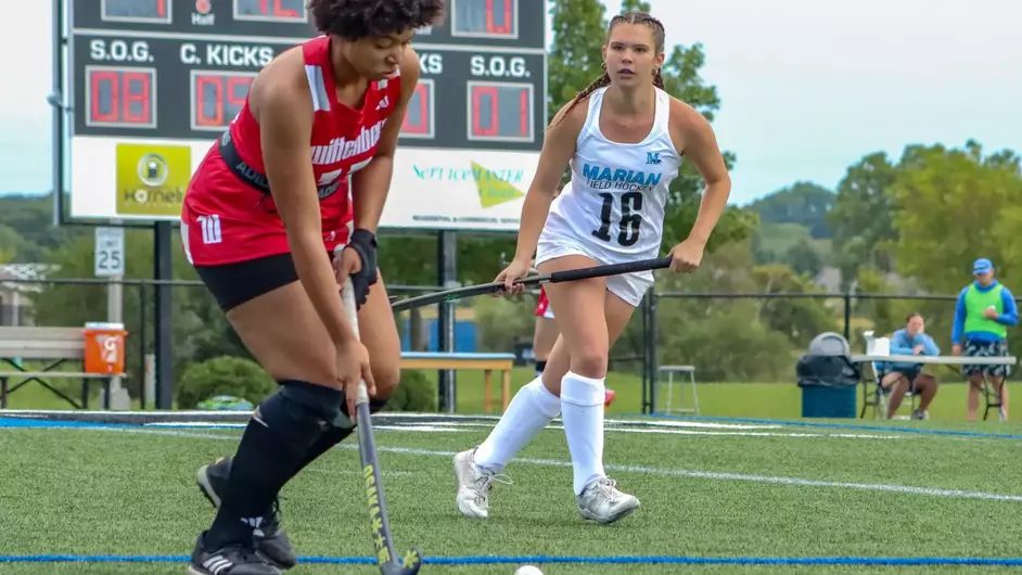 Women playing college field hockey