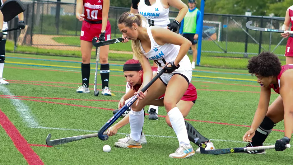 Women playing college field hockey