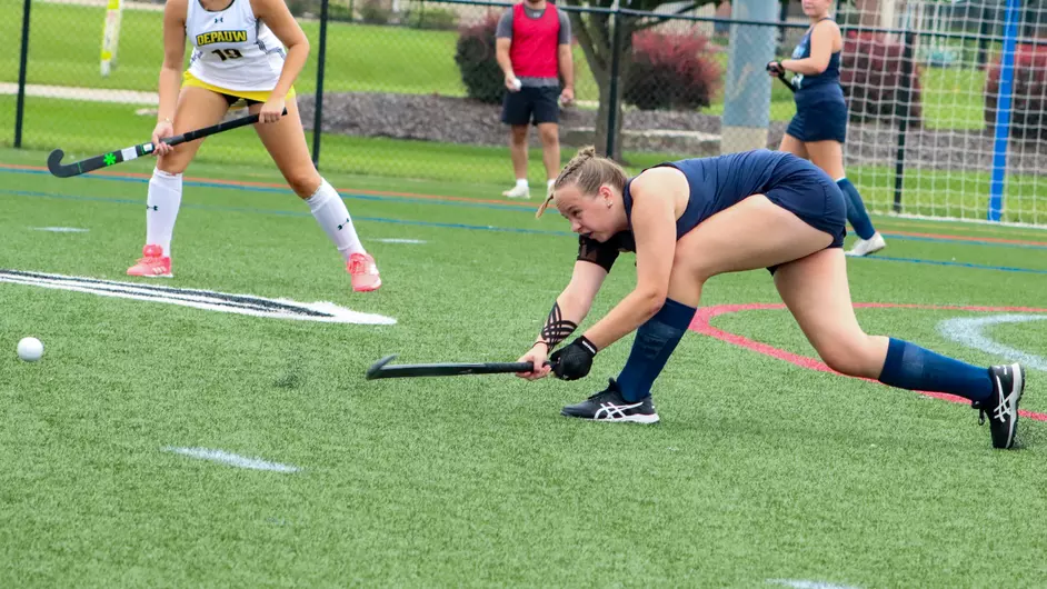 Women playing college field hockey