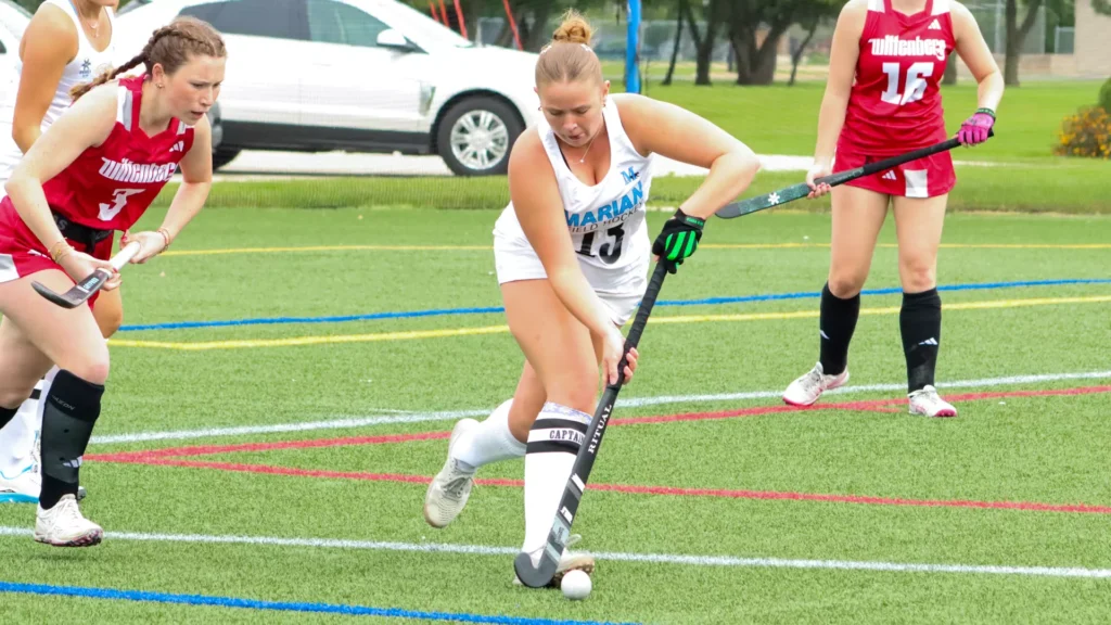 Women playing college field hockey