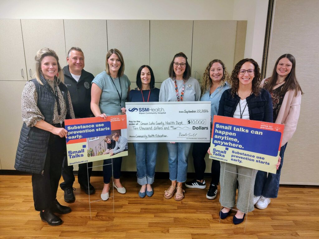 Eight people standing inside with a big check