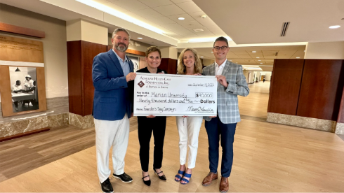 Four people holding a big check
