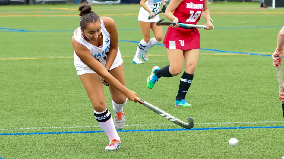 Women playing college field hockey